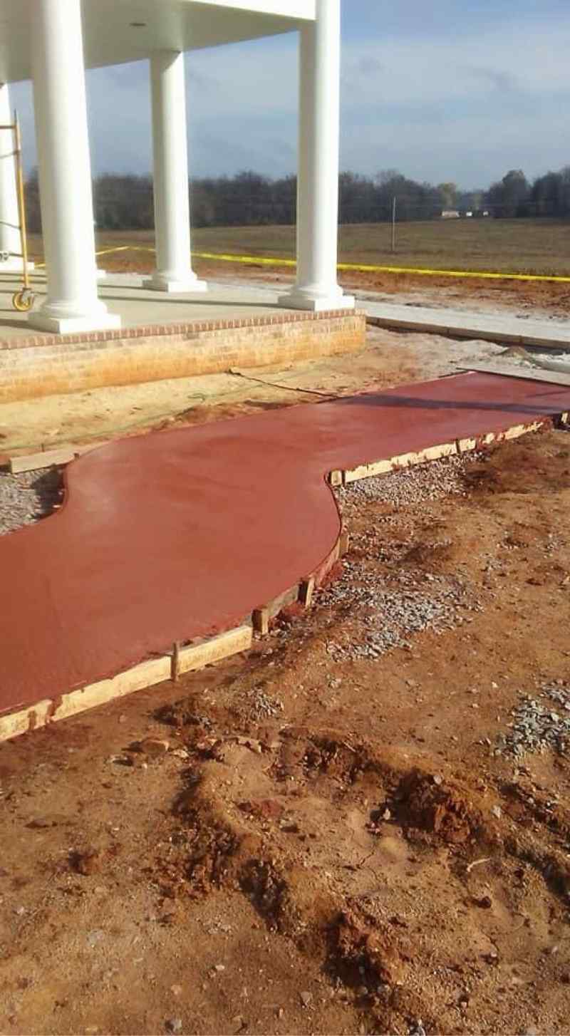 Red colored stamped concrete walkway to a porch