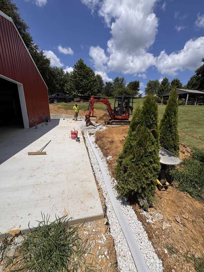 Fresh concrete slab poured beside a red barn