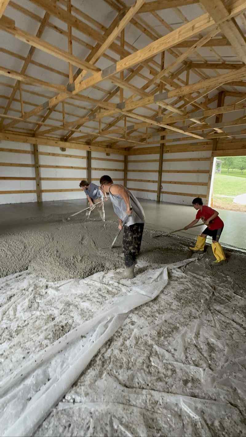 Workers pouring a concrete floor inside a barn