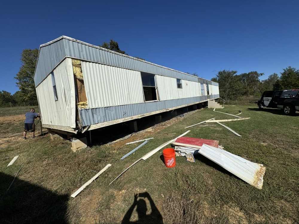 Old damaged metal siding being removed from a mobile home