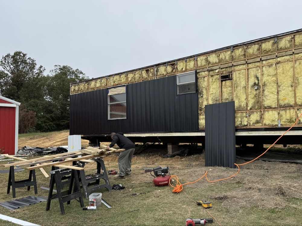 Worker installing new black metal siding panels
